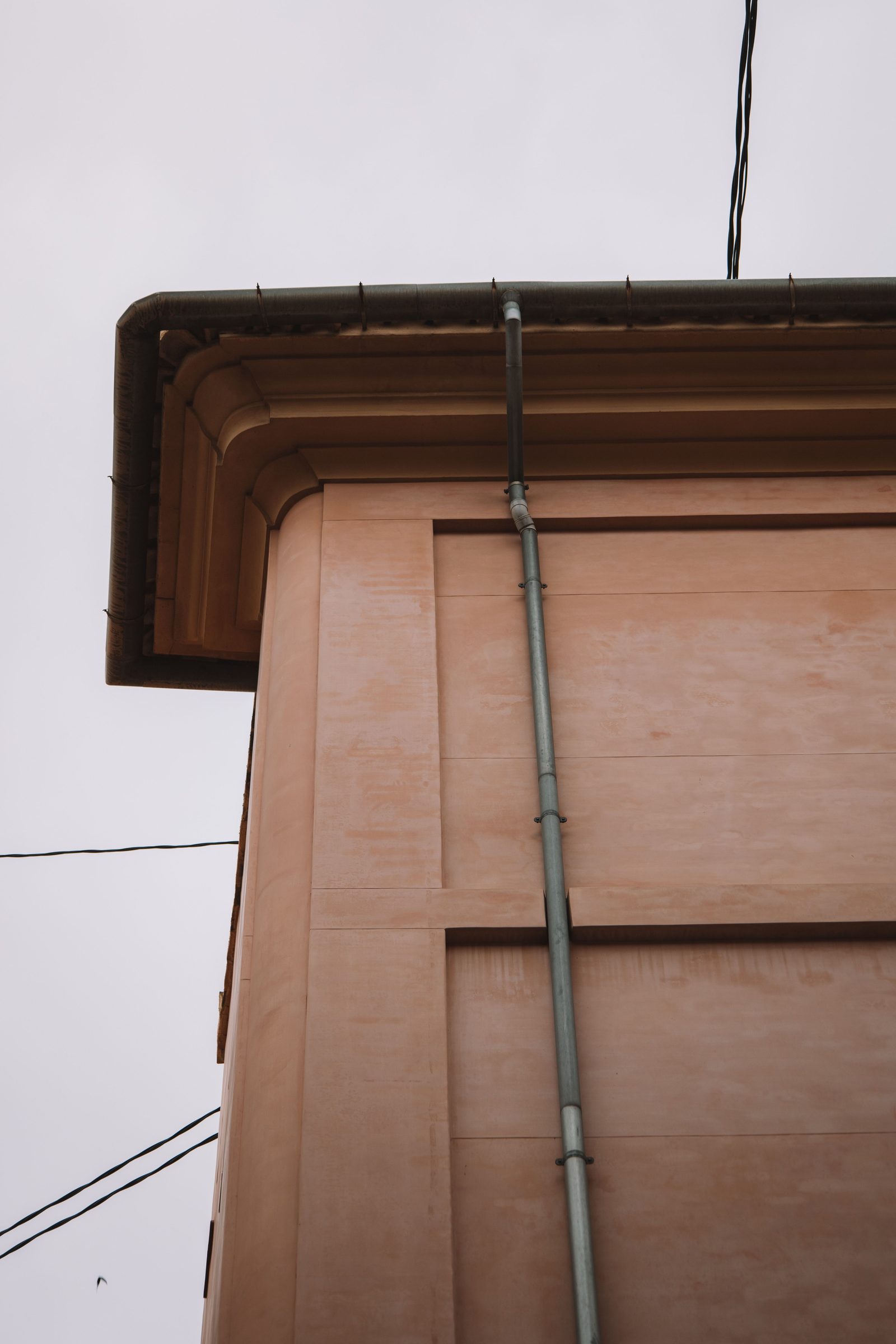 Rendered house wall with downpipe before soft washing